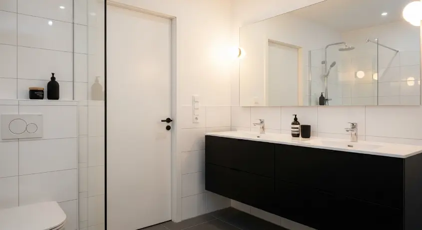 A cohesive minimalist bathroom with white tiles, a black vanity