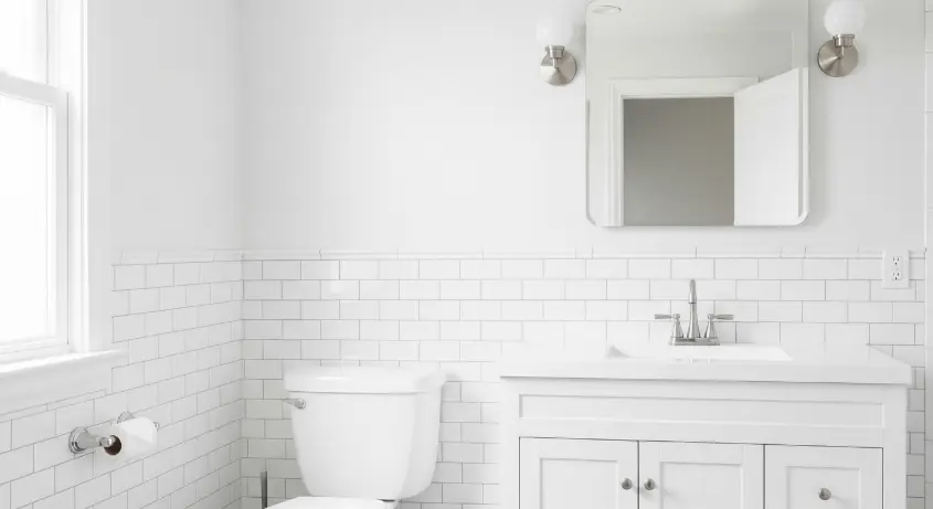 A minimalist bathroom with crisp white walls, peel-and-stick subway tiles, and a white vanity.